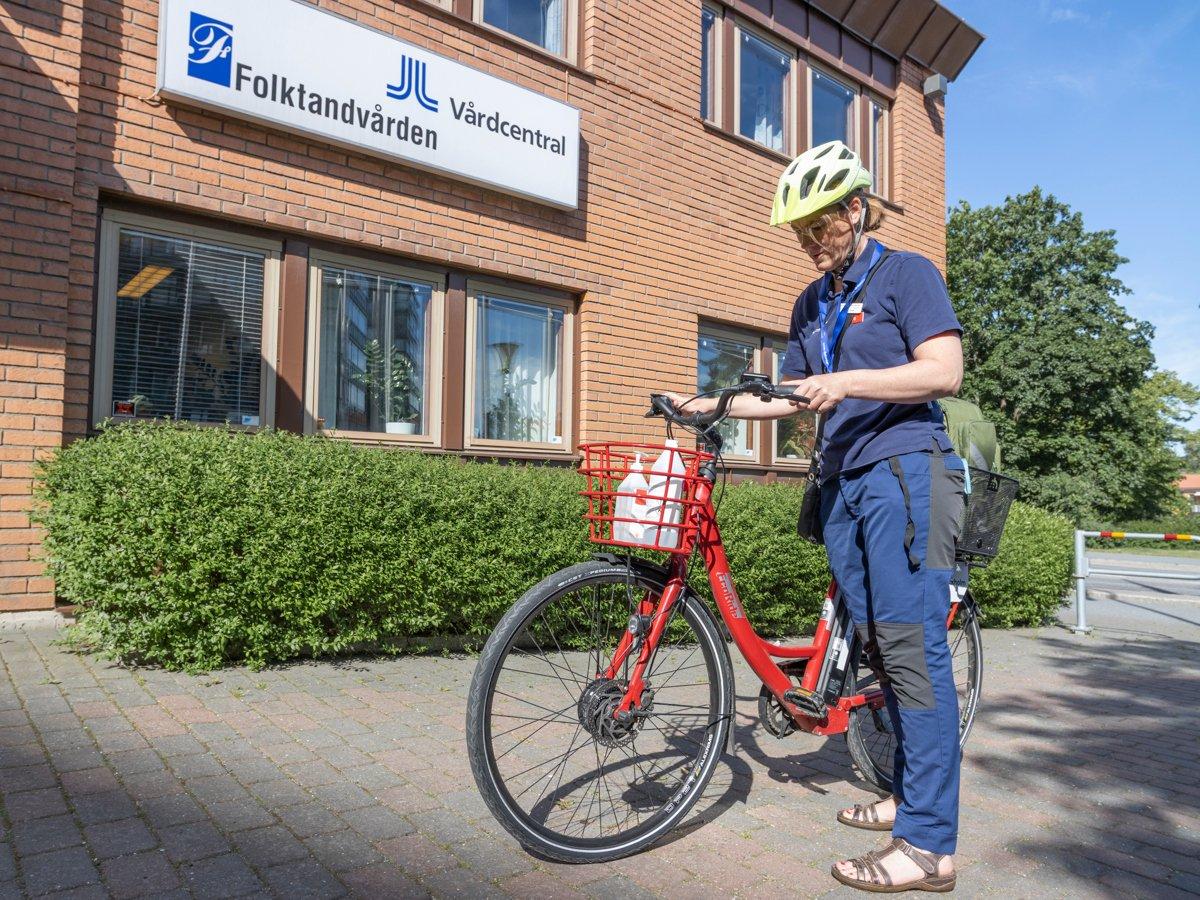 Foto på en person klädd i sjukhuskläder vid en cykel.